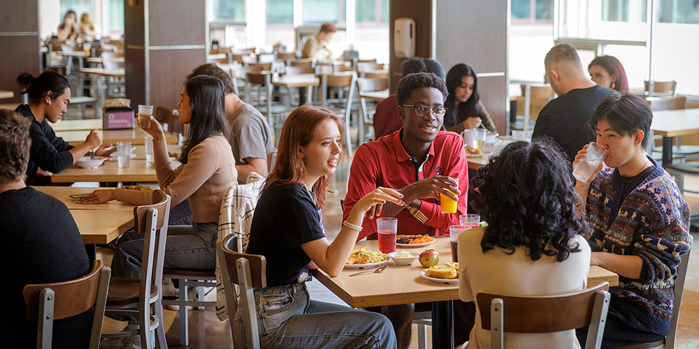 Students sitting around a table eating and talking.