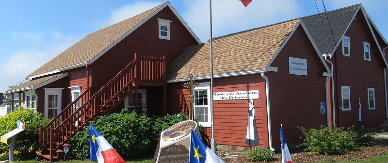A photo of a museum in Pubnico, with Acadian flags in front of it.