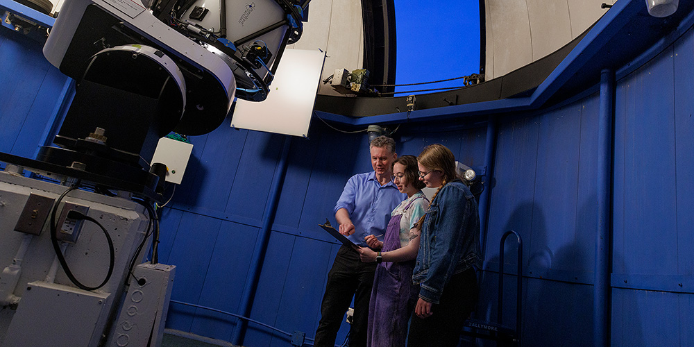 A professor and two students in in the observatory