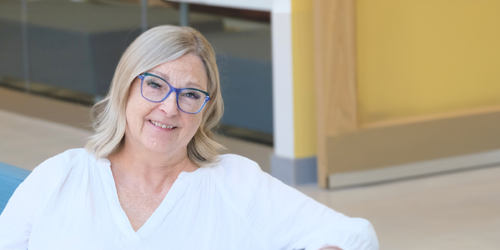 A woman smiling and posing for a photo, sitting in a professional setting.
