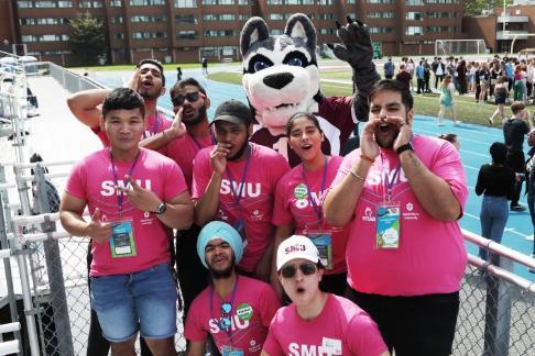 7 pack leaders standing with the Husky on the football field