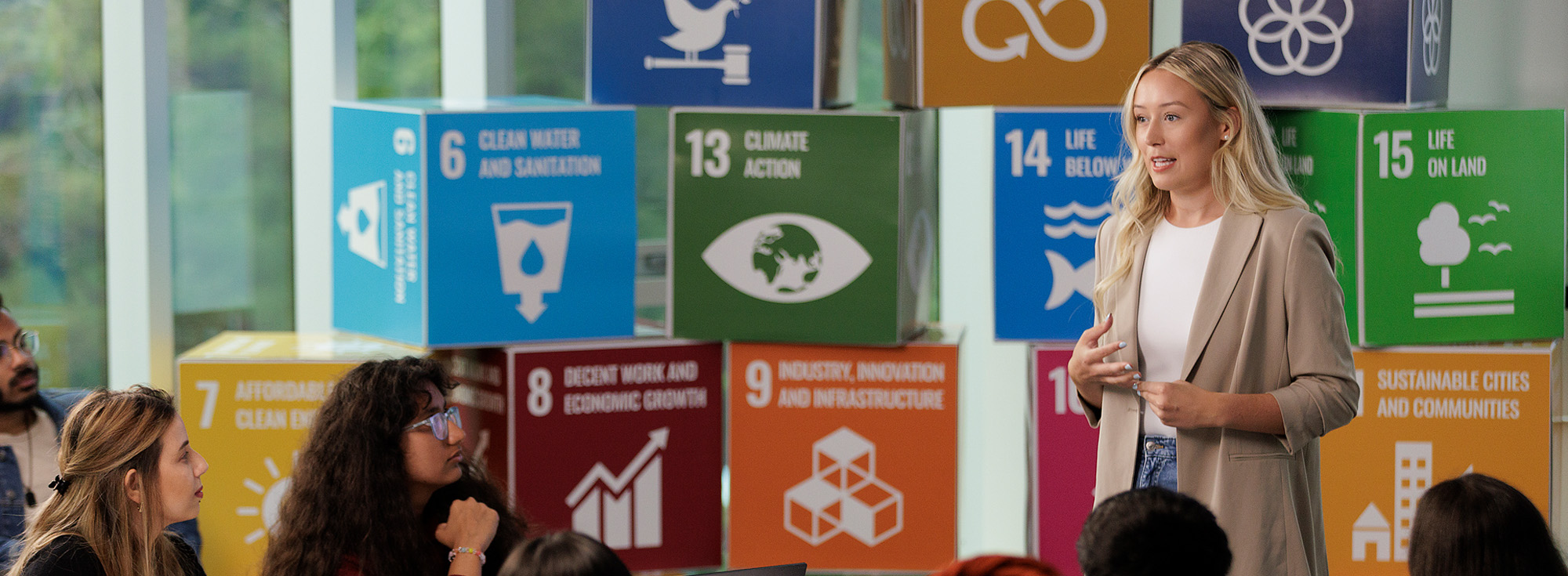 A student is giving a presentation with colourful cubes behind them.