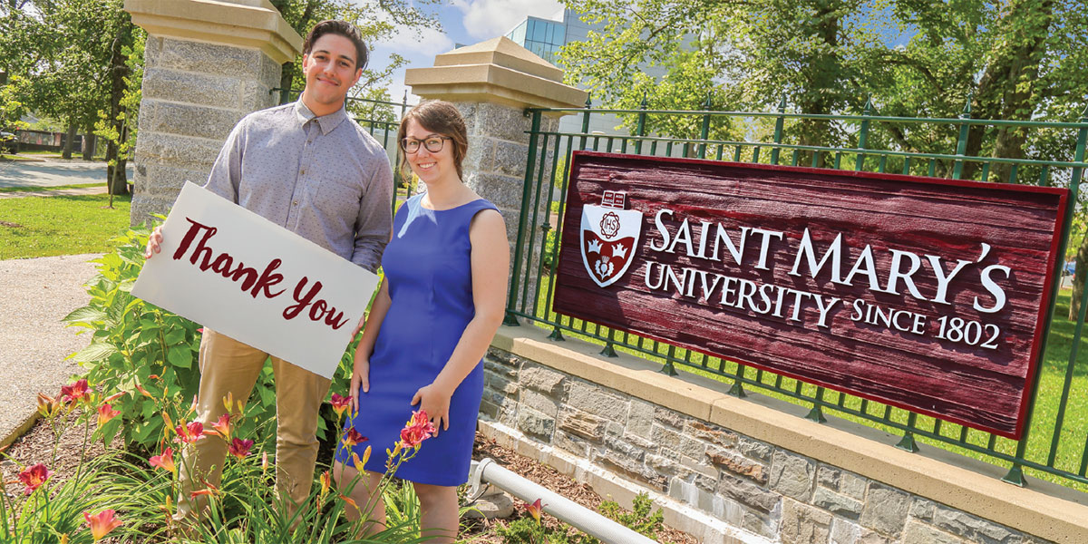 Two students holding a thank you sign