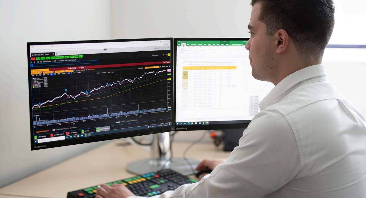 A student sitting in front of a computer with graphs on the screen.